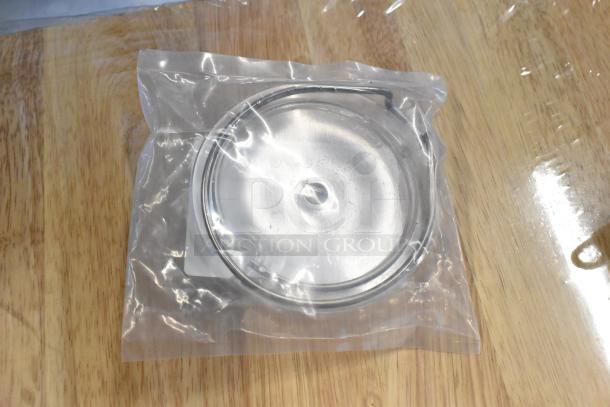 Stainless steel lid in original packaging, pristine condition, protective plastic wrap, 4-inch diameter.