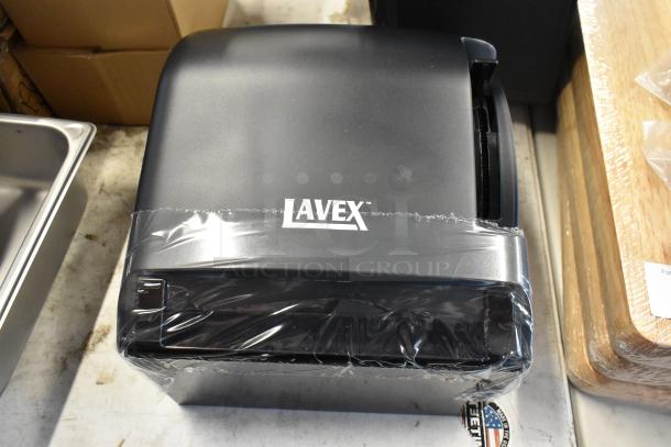 Lavex black paper towel dispenser, new in wrap, logo visible, compact design, suitable for commercial use.