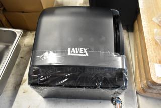Lavex black paper towel dispenser, new in wrap, logo visible, compact design, suitable for commercial use.