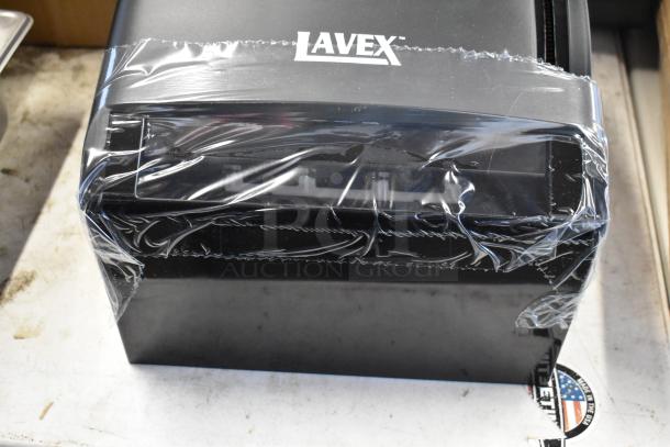 Lavex black industrial dispenser, new condition, wrapped in protective plastic. Brand logo visible on top.