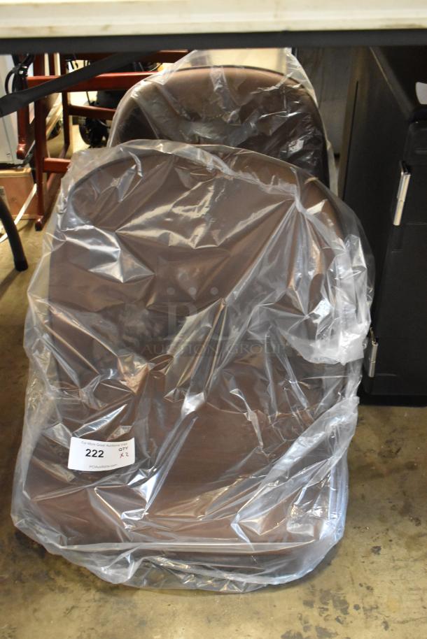 Brown chair in plastic wrap, new condition. Auction tag number 222 visible.