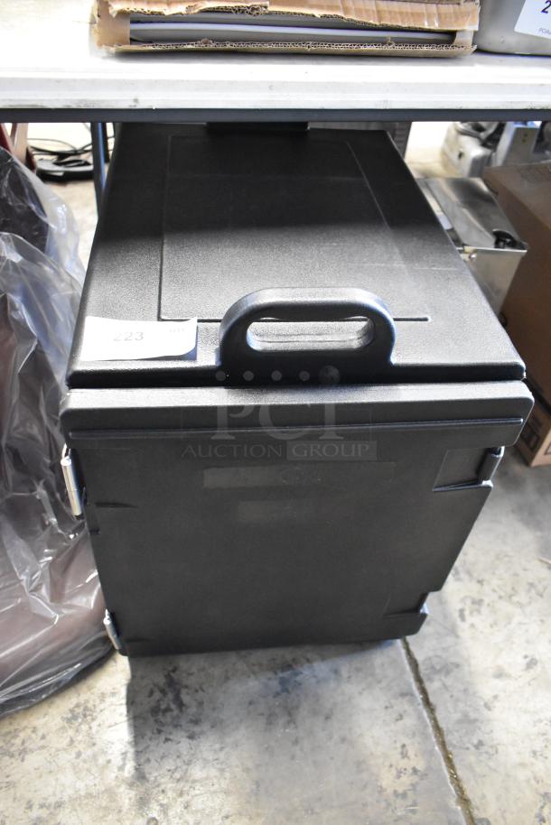Black insulated transport container with a handle, used condition. Label with "223" on top. Hinges visible on the side.