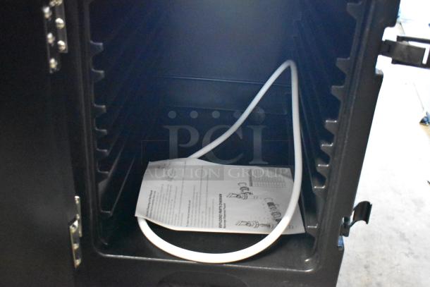 Inside view of a black cabinet with adjustable shelving, a white hose, and an instructional paper. New condition.