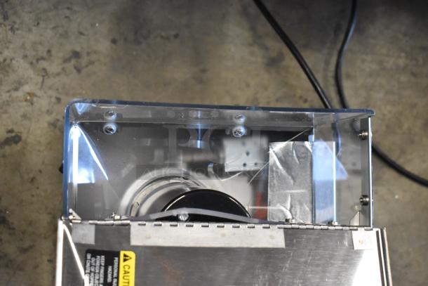 Industrial component with metal casing, visible wiring, and caution label. Clear and metallic parts, appears in used condition.