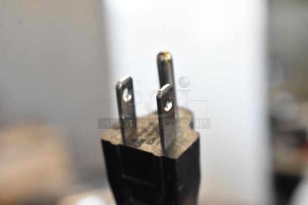 Close-up of a three-prong electrical plug in good condition, with visible metal prongs and black plastic casing.