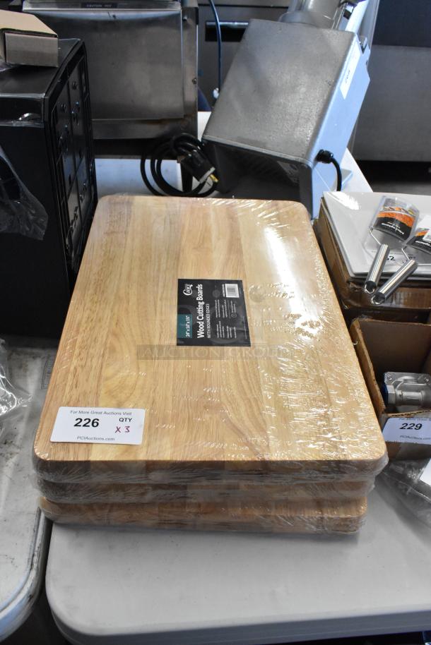 Three new wooden cutting boards, shrink-wrapped, with item tag showing "Lot 226, Qty 3" for auction identification.