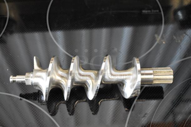 Metallic auger screw with spiral design, polished finish, used condition, likely for an industrial or kitchen appliance.