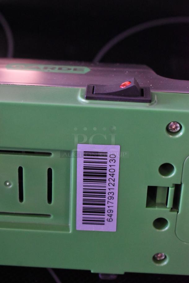 Green electronic device with a barcode label showing number 649179312240130. Features include a control switch and vent slots.