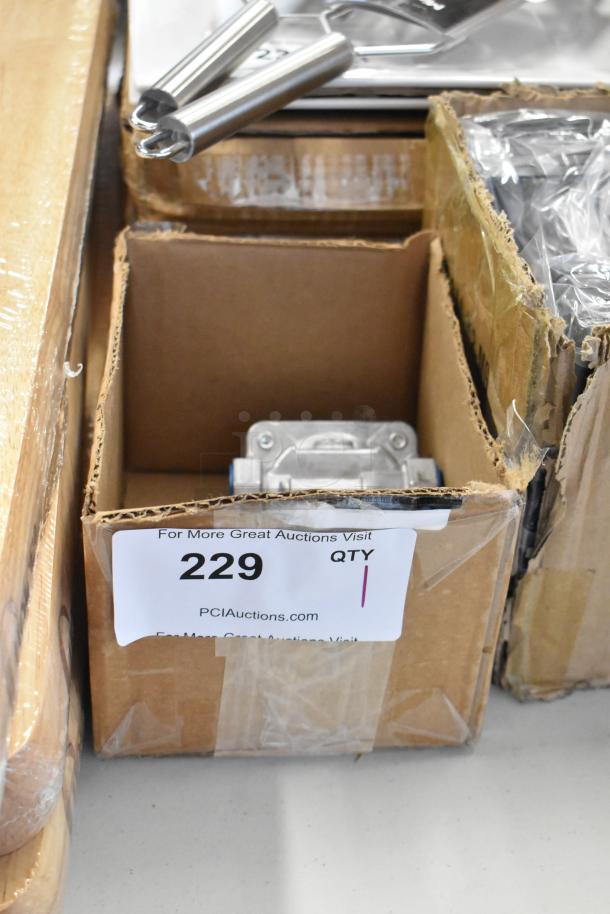 Cardboard box containing metal kitchen tools, labeled "229 QTY" from PCIAuctions.com.