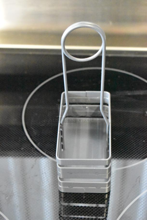 Silver metal napkin holder with a circular handle, sleek design, in excellent condition. Ideal for home or restaurant use.
