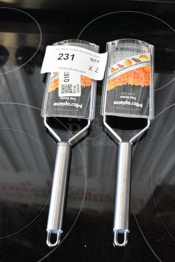 Two new Microplane fine graters with stainless steel handles on an electric stovetop, auction label "231" visible.