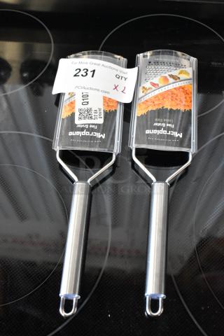 Two new Microplane fine graters with stainless steel handles on an electric stovetop, auction label "231" visible.