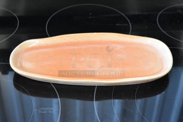 Oval ceramic platter in peach glaze, smooth finish, excellent condition. Ideal for serving or display, no visible markings.