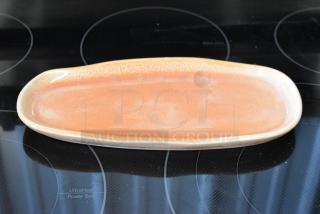 Oval ceramic platter in peach glaze, smooth finish, excellent condition. Ideal for serving or display, no visible markings.