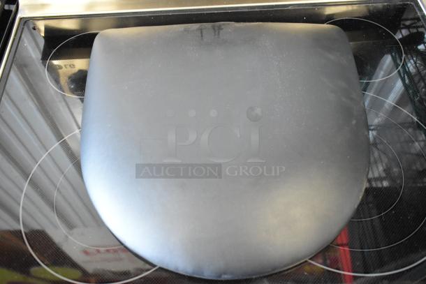 Black Stax living hinge bag laying on a glass top stove, possibly made of silicone or rubber, in good condition.