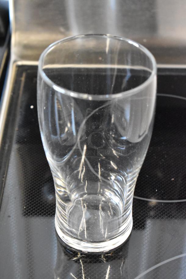 Clear glass drinking tumbler, gently curved design, in excellent condition, shown on a black surface. 