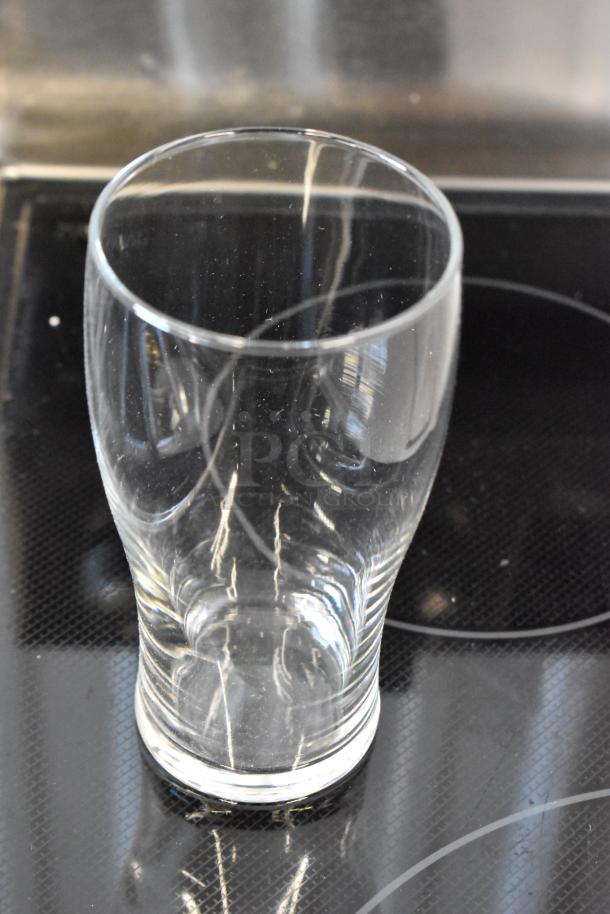 Clear glass pint glass, in excellent condition, with smooth rim and slight reflections visible on its surface.
