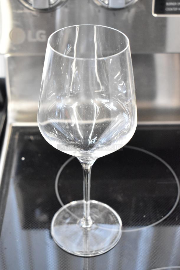 Clear crystal wine glass with long stem, in excellent condition, no visible markings, displayed on stove surface.
