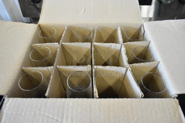 Open box containing twelve cylindrical glassware pieces in separate cardboard compartments, appears new and unused.