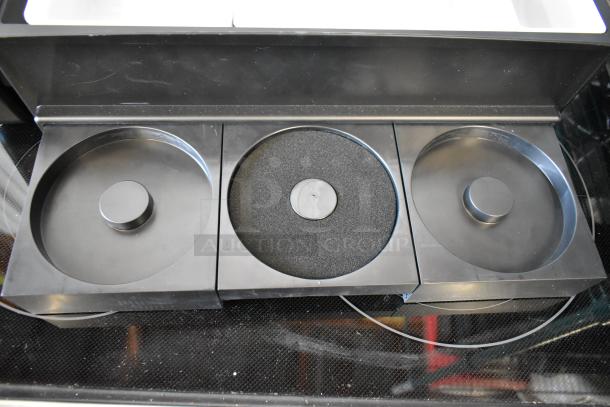 Three black puck-style caster mounts in a box; two with a flat top, one with a textured surface.