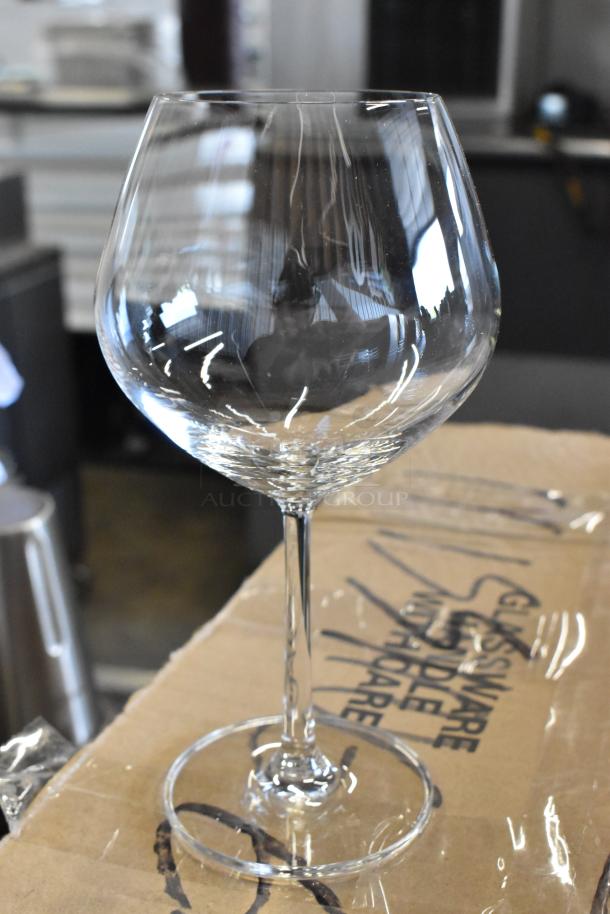 Clear wine glass on cardboard box, gently used. Box text reads "Glassware Handle with Care." Stemware in excellent condition.