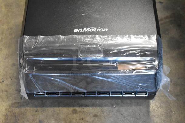 Black enMotion automated paper towel dispenser, unopened, with protective plastic wrap, featuring enMotion branding.