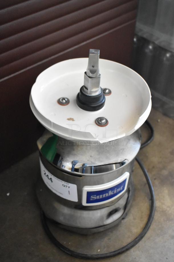 Sunkist commercial juicer with stainless steel body and plastic top. Minor wear visible. Model and quantity labels attached.