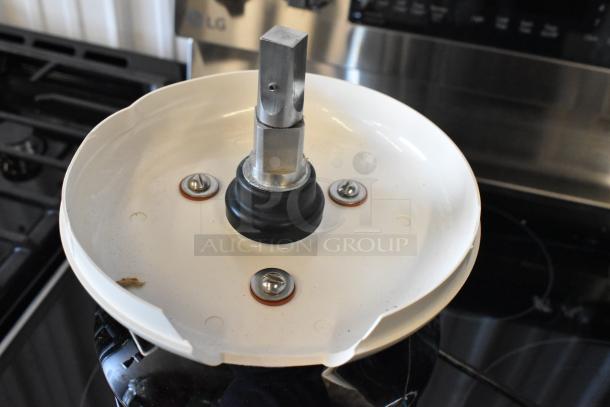 Metal mechanical component with white circular base, three screws, and central metal shaft, in good condition.