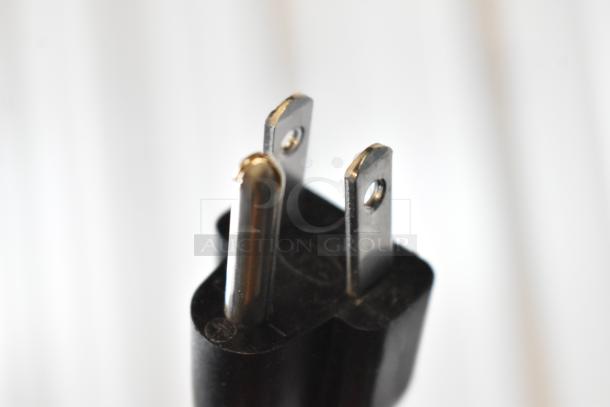 Close-up of a standard U.S. three-prong electrical plug with black casing and metallic pins, in good condition.