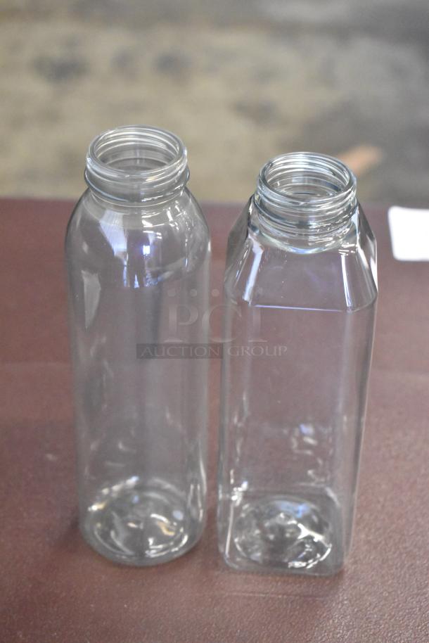 Two clear glass bottles, one cylindrical and one square-shaped, in pristine condition. No visible labels.
