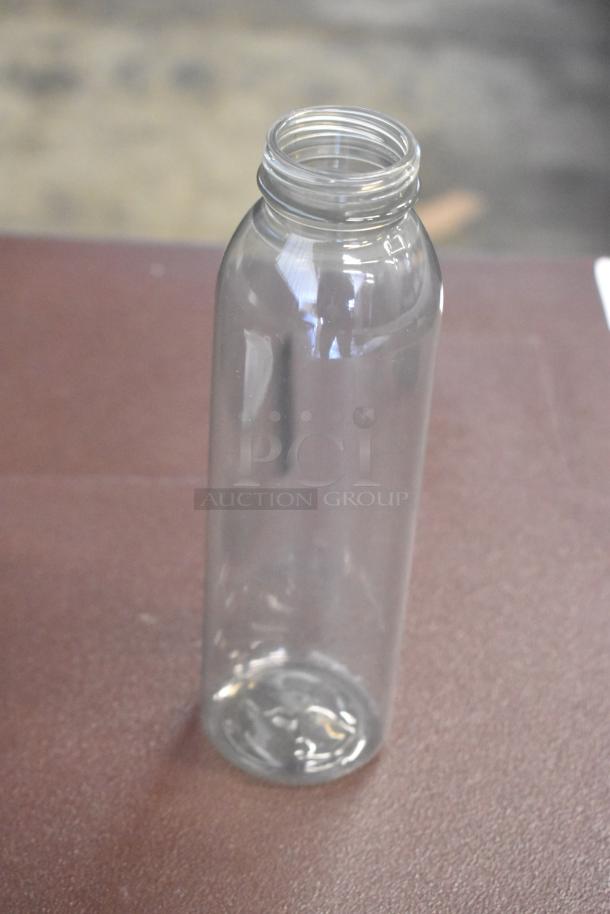 Clear glass bottle, cylindrical shape, wide mouth, in excellent condition on a brown surface. No labels or markings visible.