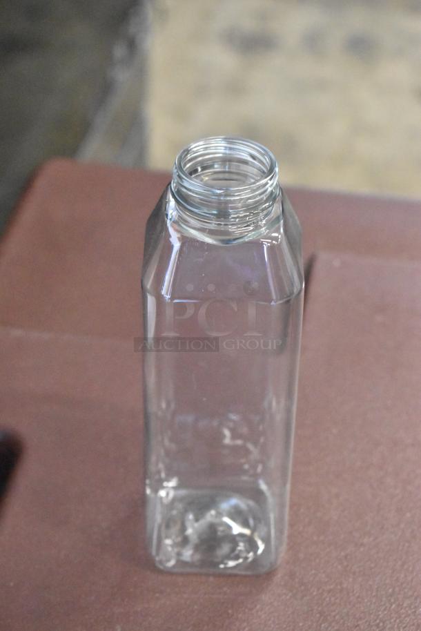 Clear square glass bottle, open top, standing on a surface. Excellent condition, ideal for storage or decor.