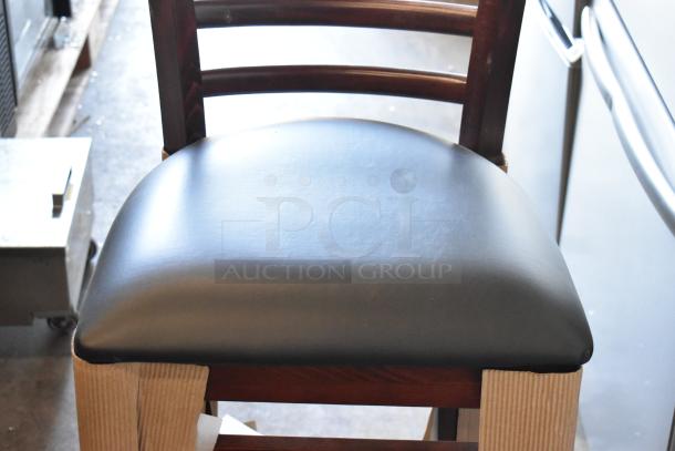 Black cushioned chair with wooden frame, leather upholstery, in excellent condition. Cardboard protective covers visible.