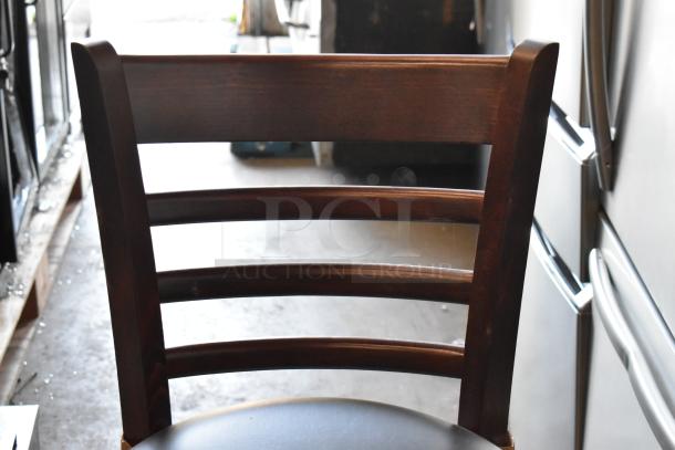 Wooden ladder-back chair with dark finish, slightly worn, features a curved seat. Appears sturdy with minor scratches.