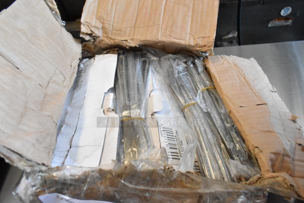 Open box containing multiple plastic-wrapped metal rods secured with rubber bands. Box shows wear; visible label includes a barcode.