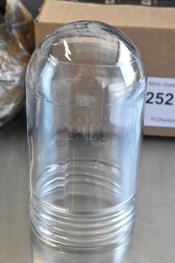 Clear glass dome-shaped cover with grooved base, possibly a replacement part, in excellent condition on metallic surface.