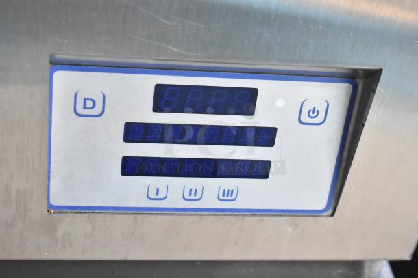 Digital control panel on stainless steel appliance, features buttons, display screen, and power icon, slightly worn condition.
