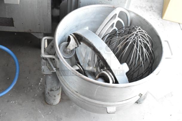 Industrial mixer bowl with attachments, including wire whisk and dough hook, in used condition. Steel construction, sturdy design.