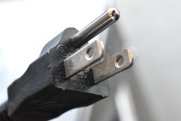 Close-up of a three-prong black power plug with visible markings, indicating specifications and approvals.