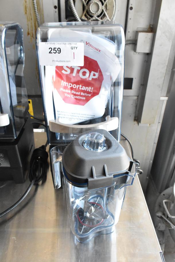 Vitamix blender with clear container, black lid, visible blades, and caution label. Tag reads "259" with auction details.