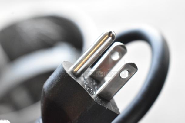 Close-up of a three-prong electrical plug with a black, flexible cable. Plug is in excellent condition.
