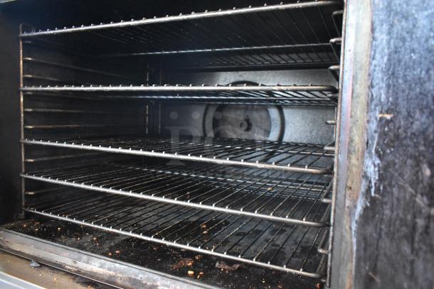 Commercial oven with multiple wire racks, visible wear and residue inside, suggesting frequent use. No visible markings.