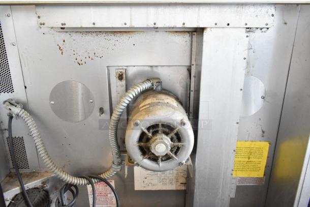Industrial fan with coiled wiring, visible wear and rust on metal casing. Safety labels and wiring diagram present.