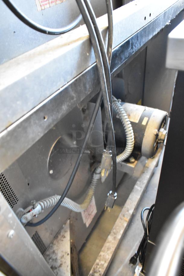 Industrial motor with power cables in a metal housing, showing moderate wear. Labels visible, indicating specifications.