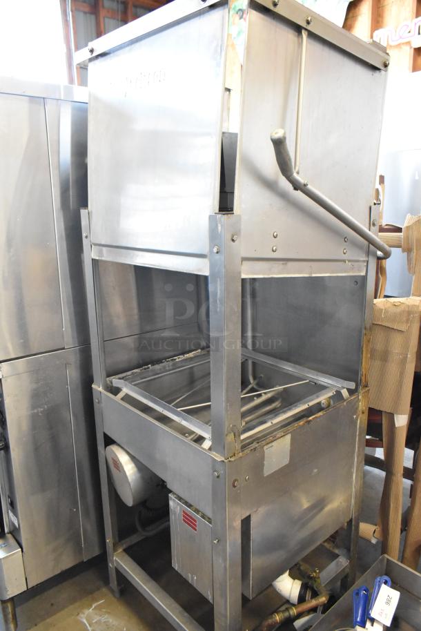 Commercial stainless steel dishwasher, used condition. Features a manual handle, visible wear, and utility connections. Suitable for industrial kitchen.