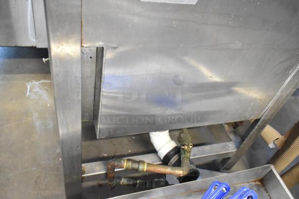 Stainless steel commercial sink with visible plumbing, slight dent on front. Used condition, ideal for kitchen setups.