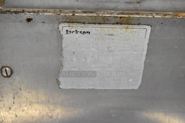 Metal surface with worn "Jackson" label, showing signs of rust and wear. Label partially illegible, suggests company branding.