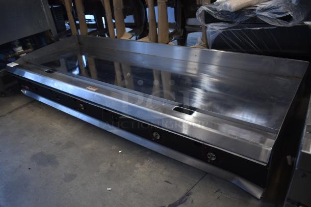 Commercial stainless steel griddle with multiple burners, used condition, visible control knobs, and minor surface wear.