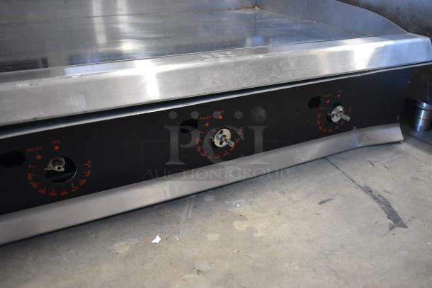 Commercial stainless steel griddle with three temperature dials; minor surface wear, suitable for restaurant use.