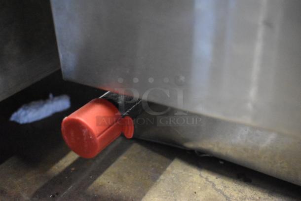 Close-up of a stainless steel appliance with a red handle attachment in good condition, likely part of a kitchen or industrial equipment.